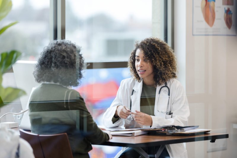 Sitting in office, doctor has serious conversation with patient