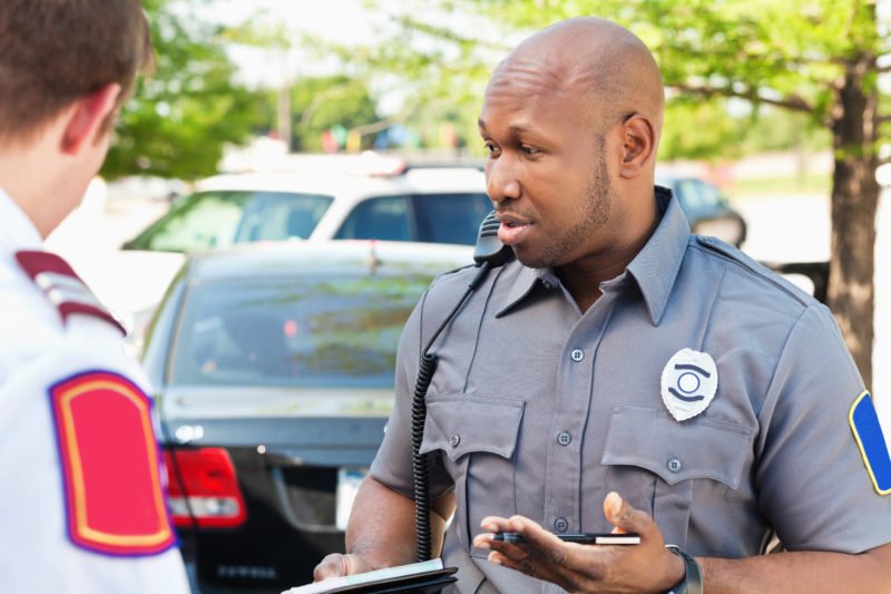 Police officer interogating people at an emergency scene.