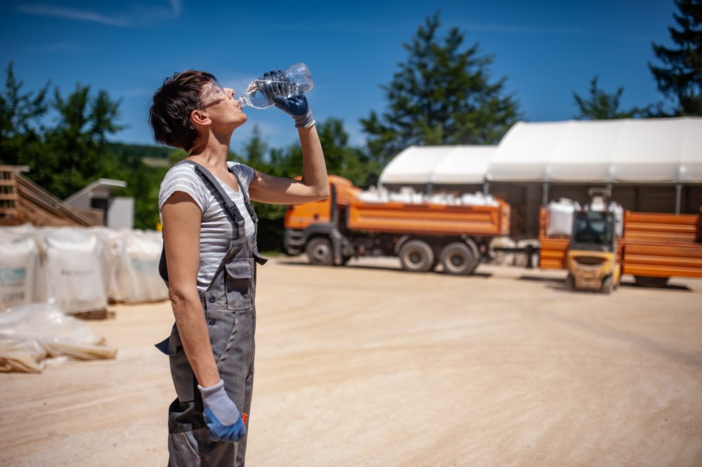 A woman drinking water outside. 